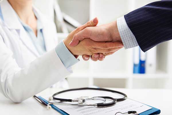 Clinician and patient shaking hands over a form